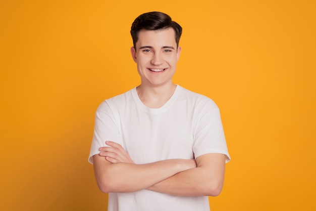 Portrait of happy handsome man crossing hands isolated over yellow background