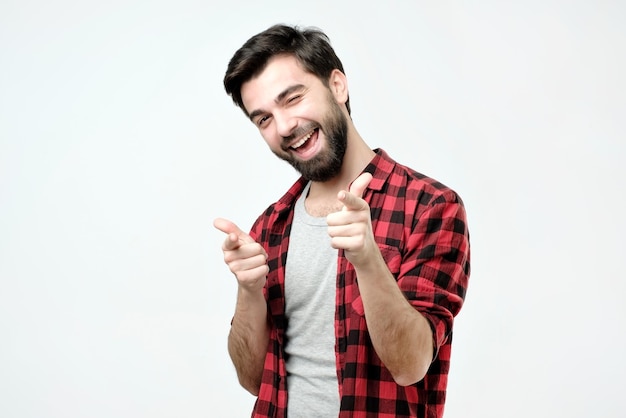 Portrait of happy hispanic man with beard pointing at you