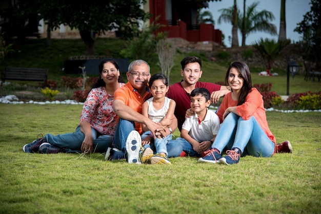 Photo portrait of happy indian asian family while sitting on lawn, outdoor