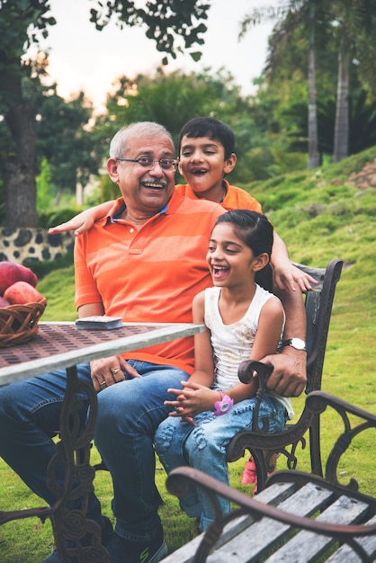 Portrait of Happy Indian Asian Kids and grandfather sitting on lawn chair