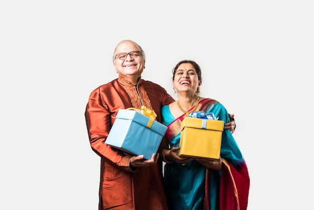 Portrait of Happy Indian asian senior or retired couple holding gift boxes isolated over white background