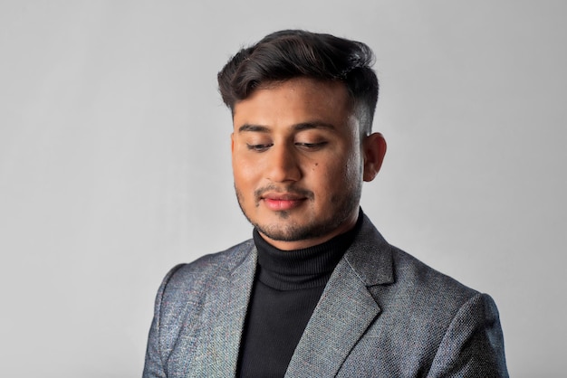 Portrait of Happy Indian young man businessman wearing a blazer on grey background posing satisfied successful male in formal suit