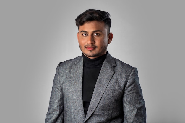 Portrait of Happy Indian young man businessman wearing a blazer on grey background posing satisfied successful male in formal suit