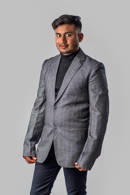 Portrait of Happy Indian young man businessman wearing a blazer on grey background posing satisfied successful male in formal suit