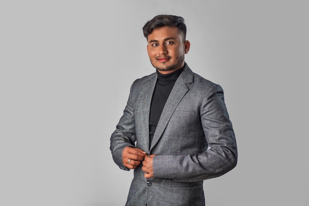 Portrait of Happy Indian young man businessman wearing a blazer on grey background posing satisfied successful male in formal suit
