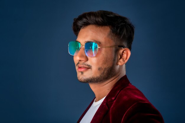 Portrait of Happy Indian young man wearing a blazer with eyeglasses posing on a blue background