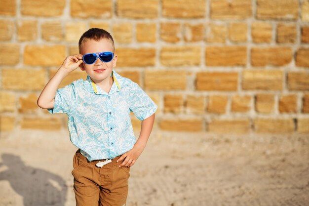 Portrait of happy joyful beautiful little boy in front of yellow brick wall. 