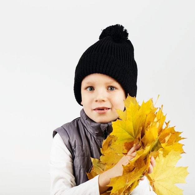 Portrait of happy joyful beautiful little boy with autumn foliage