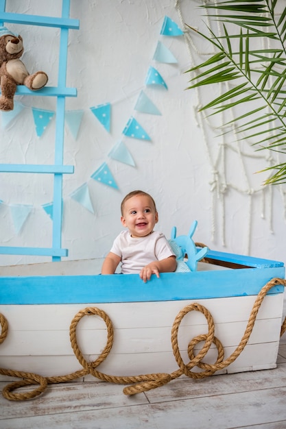 Portrait of a happy kid boy sitting in a wooden boat