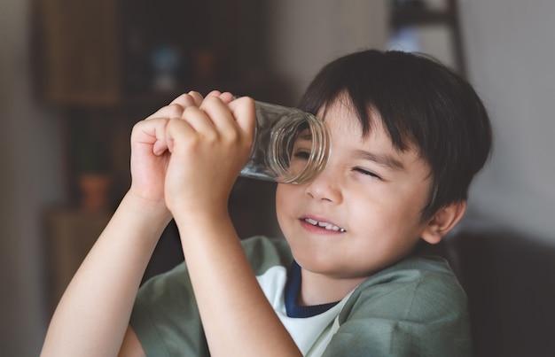 Portrait of Happy kid looking through glass jar. Play and learn at home, exploration concept