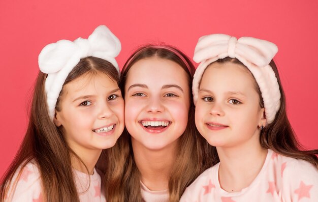 Портрет счастливых детей с улыбающимися лицами на розовом фоне домашней одежды