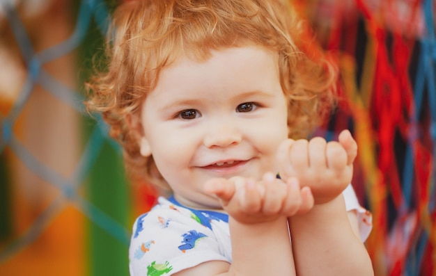 Portrait of a happy laughing baby child on playground Close up positive kids face