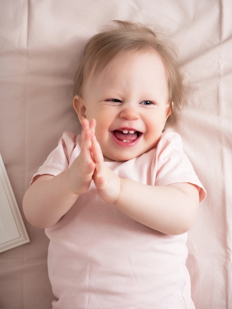 Foto ritratto di un bambino che ride felice, con un'espressione divertente sul viso. una piccola bella ragazza con gli occhi azzurri sorride allegramente, i primi denti sono visibili.