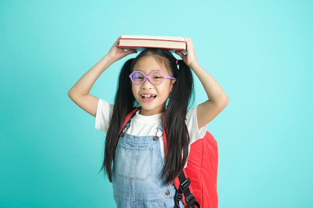 Portrait of happy lazy little girl covering head with book and smiling to camera