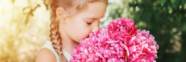 portrait of a happy little caucasian seven year old kid girl, holds in hands and smell and enjoying