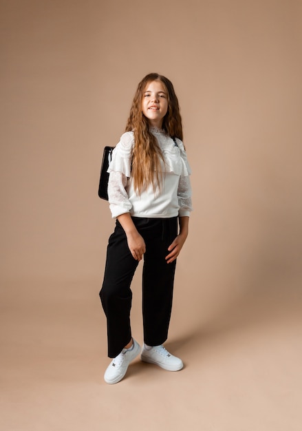 Photo portrait of happy little girl 12 years old standing and posing on studio background