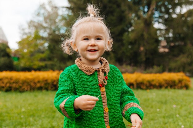 Portrait of a happy little girl in autumn clothes. the child laughs against the background of nature.