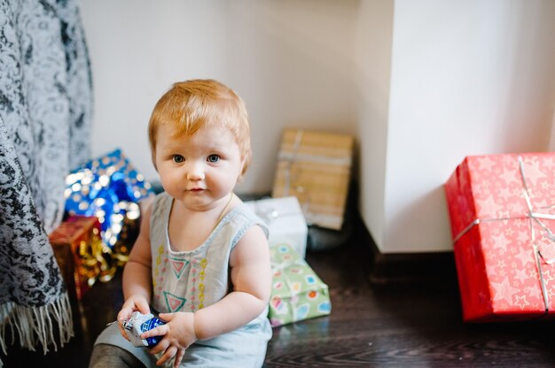 Portrait happy little girl playing with toys, next to christmas gifts.