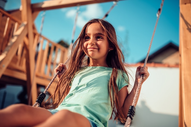 Portrait of a happy little girl sitting on a swing