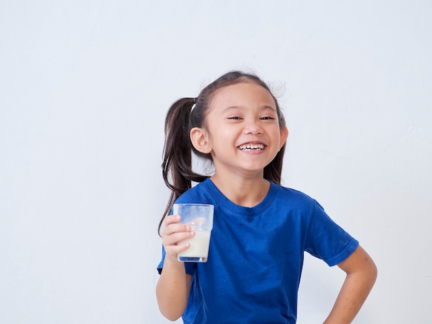 Portrait of happy little girl with glass of milk on light