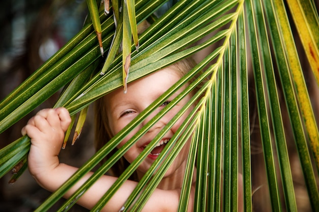 Portrait of happy little girl with palm leaf. 