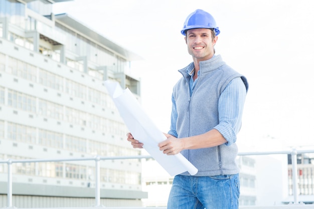 Foto ritratto del modello maschio felice della tenuta dell'architetto fuori dell'edificio per uffici