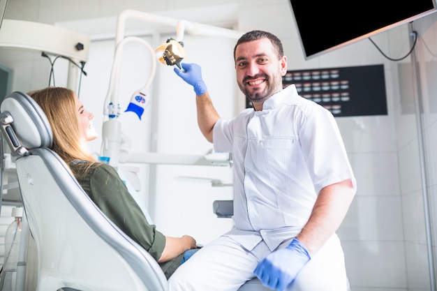 Portrait of a happy male dentist examining female's teeth