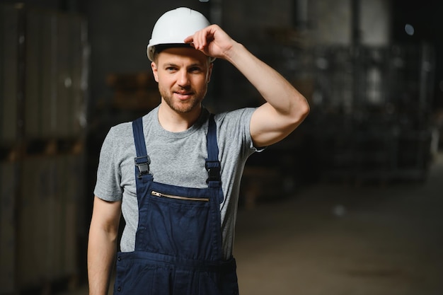 Portrait of happy male worker in warehouse standing between shelves