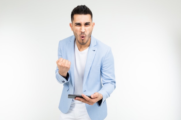 Portrait of a happy man in a blue jacket playing a game on a smartphone in a horizontal position