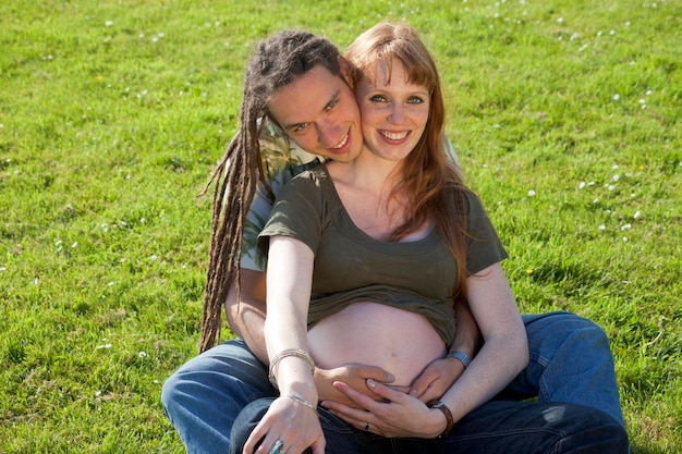 Photo portrait of happy man embracing pregnant girlfriend sitting on grassy field