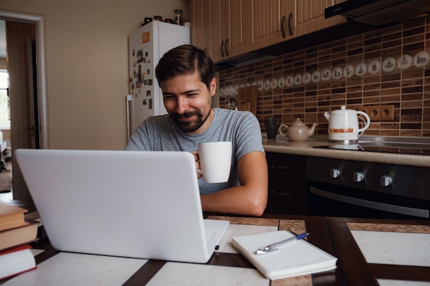 キッチンで一杯のコーヒーを持っている幸せな男の肖像