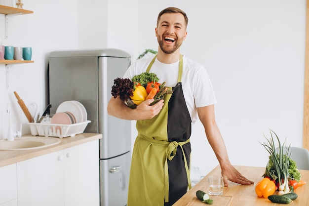 キッチンで新鮮な野菜のプレートを保持している幸せな男の肖像画