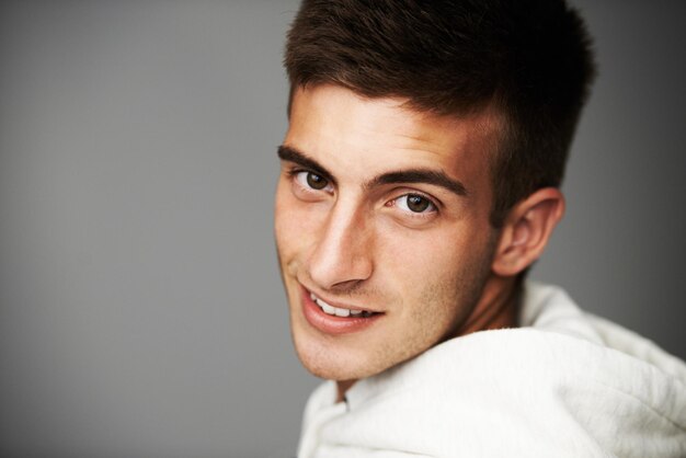 Foto ritratto felice e uomo con cappuccio per la moda isolato su uno spazio di mockup di sfondo grigio dello studio persona sorriso viso di modello e abiti eleganti espressione facciale casuale o cool in spagna sullo sfondo