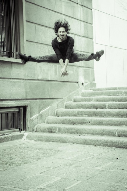 Photo portrait of happy man jumping above staircase against building