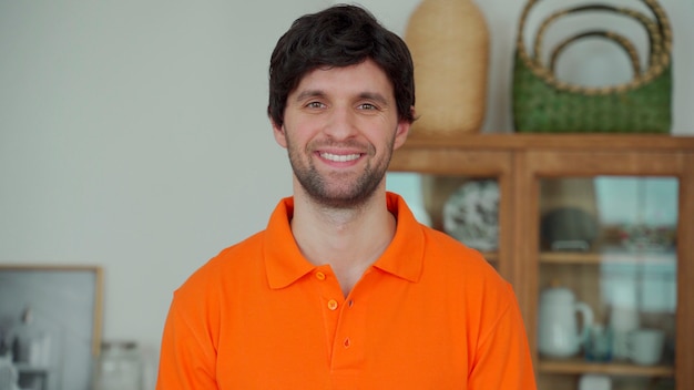 Foto ritratto di un uomo felice in una camicia arancione, guardando la telecamera e sorridente