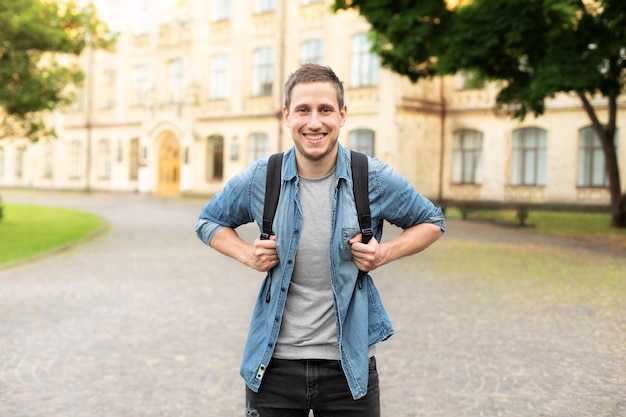 Portrait of happy man on street with backpack in the park in summer