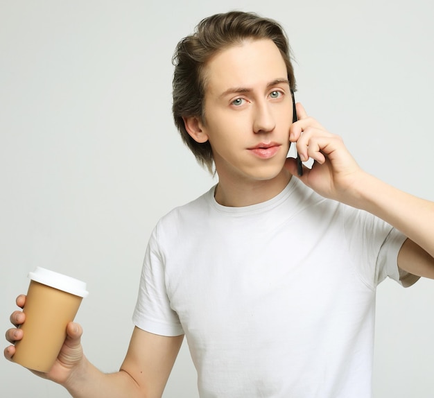 Портрет счастливого человека, разговаривающего по телефону и пьющего кофе