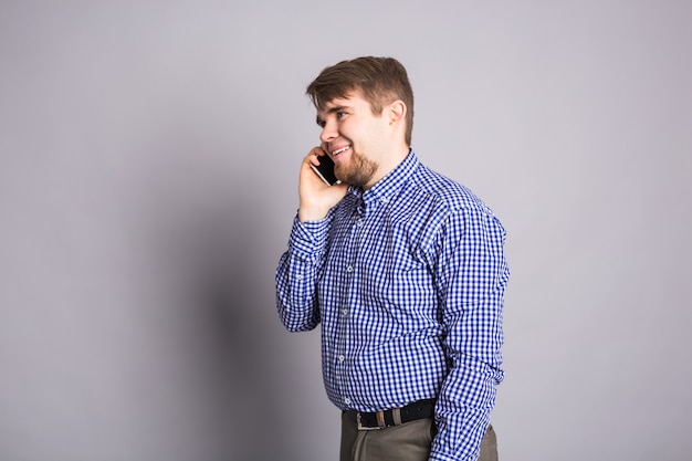 Portrait of happy man talking on phone over gray wall.