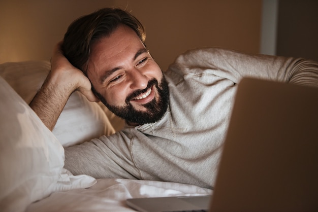 Ritratto di un uomo felice che per mezzo del computer portatile