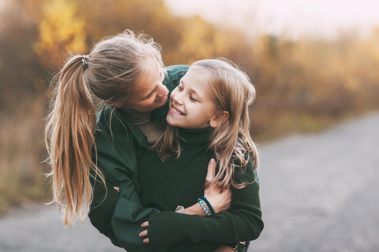 Photo portrait of happy mature mom and her blonde little daughter hugging and laughing