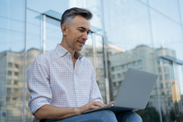 Portrait of happy mature programmer using laptop, working project