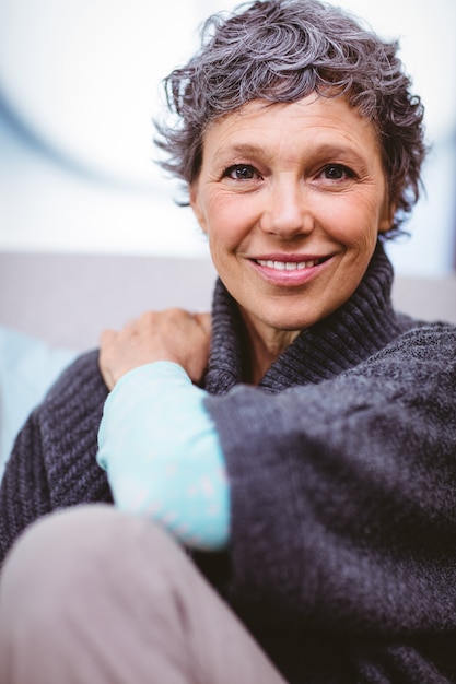 Portrait of happy mature woman sitting on sofa