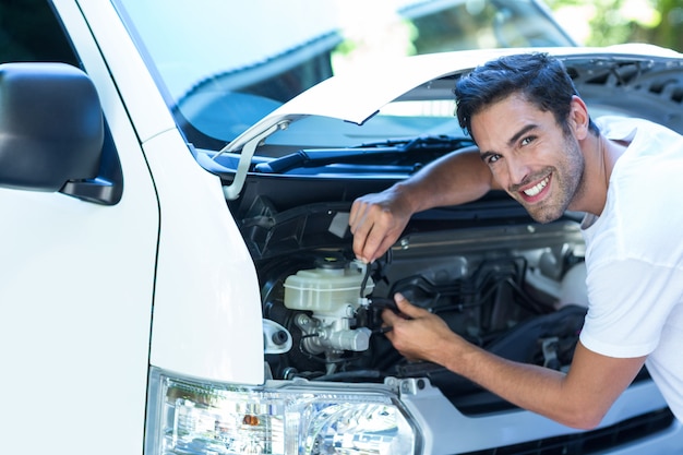 Portrait of happy mechanic fixing van