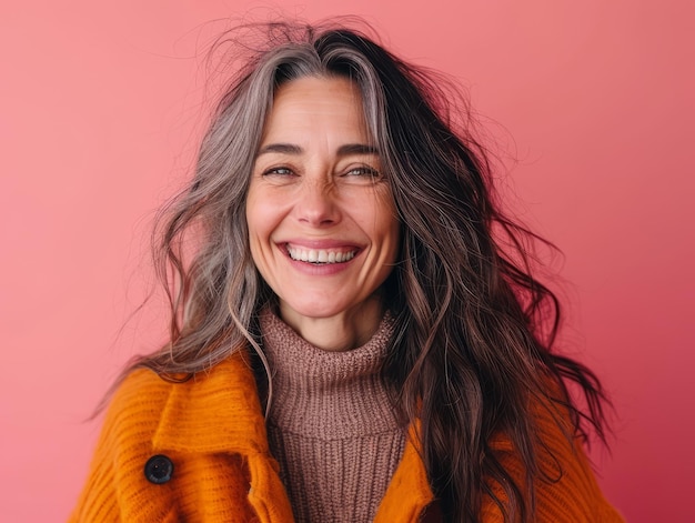 Portrait of happy middle aged woman smiling on pink background