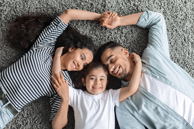 Portrait of happy middle eastern family cuddling on floor