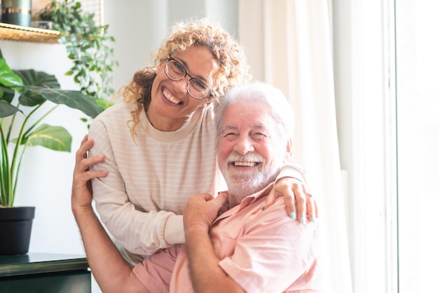 Portrait of happy middleaged woman and senior father hugging spending time together at home