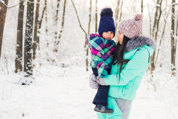 Portrait of happy mother and baby in winter park.