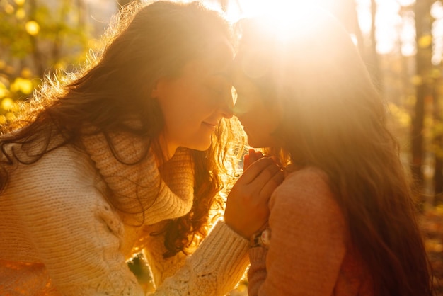 Portrait of happy mother and daughter in autumn forest at sunset Autumn women