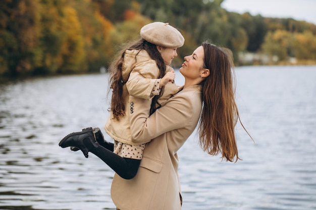 Foto ritratto di madre e figlia felici insieme nel parco autunnale con foglie gialle che cadono vicino al lago