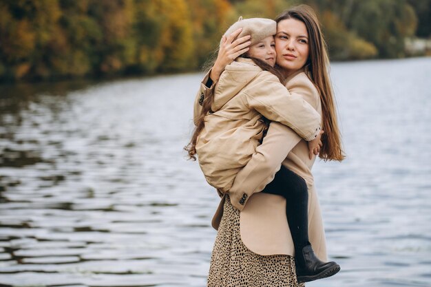 Photo portrait of happy mother and daughter together in autumn park with falling yellow leaves near lake